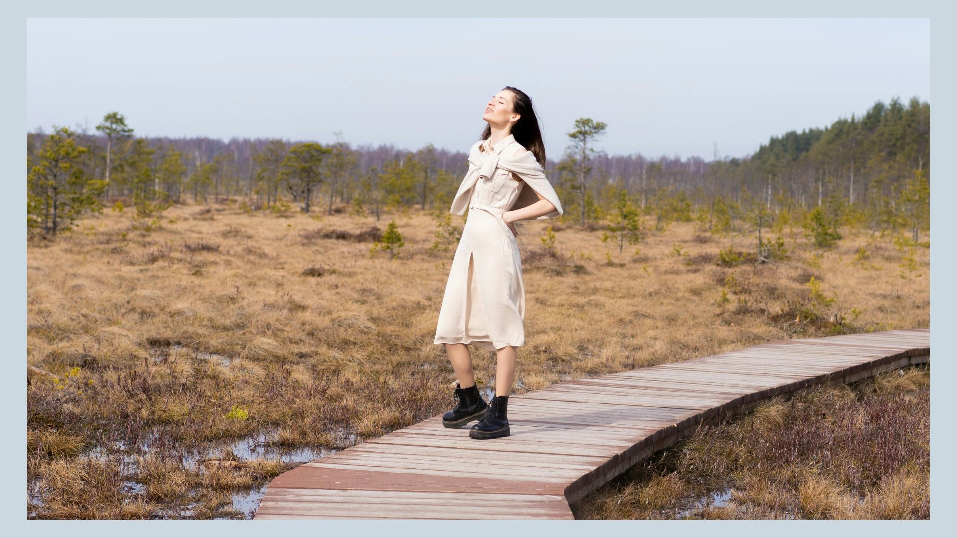 Woman in dress and boots standing in an open space